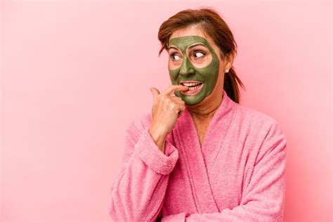 Žena s pleťovou maskou na tvári relaxujúca v kúpeľni