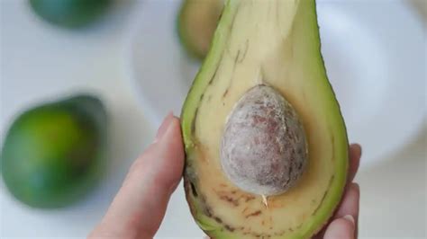 Fotografia rozpoleného avokáda s viditeľnou zelenou dužinou a kôstkou.